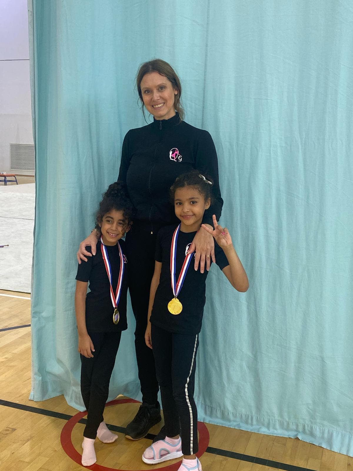 Coach Elena with two students wearing medals